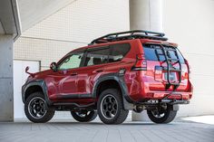 a red four - door suv parked in front of a building with no doors on it