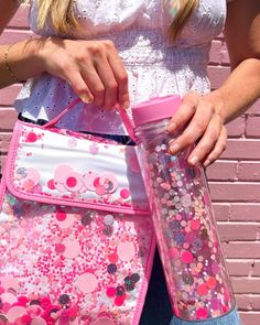 a woman is holding a pink and white bag with polka dots on it as she holds her water bottle