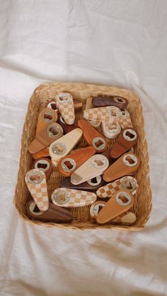 a wicker basket filled with lots of wooden buttons on top of a white sheet