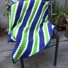 a blue and green blanket sitting on top of a chair next to potted plants