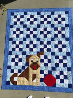 a person standing next to a blue and white quilt with a brown dog on it