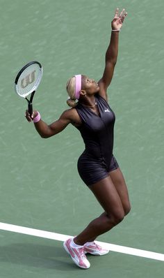 a woman holding a tennis racquet on top of a tennis court with her hand in the air