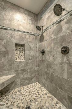 a walk in shower sitting next to a tiled wall and floor with two hand held shower heads