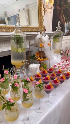 a table topped with lots of glasses filled with liquid and food on top of it