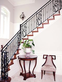 a small table with a potted plant on it next to a stair case