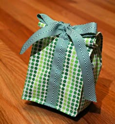 an origami box with a green and white polka dot ribbon tied around it