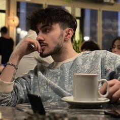 a man sitting at a table with a cup and saucer