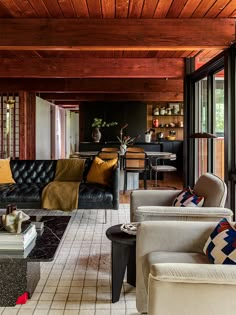 a living room filled with furniture and lots of wood paneled walls, along with windows