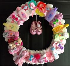 a wreath with baby items hanging from it's sides and shoes on the front door