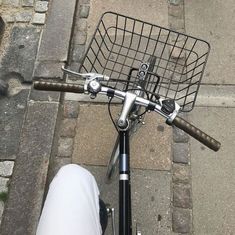 a bicycle with a basket on the handlebars parked in front of a sidewalk