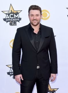 a man in a tuxedo and black shirt at an awards event with his hands in his pockets