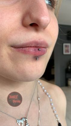 a close up of a person wearing a necklace and nose piercing with an elephant sticker on it