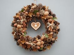 a wreath with pine cones, nuts and a heart shaped ornament hanging on the wall