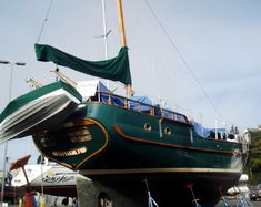 a large green boat sitting on top of a body of water next to other boats