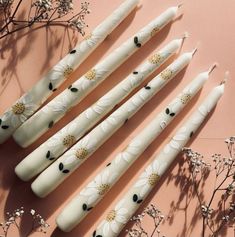 six white candles sitting on top of a pink surface