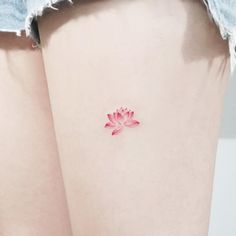 a woman's thigh with a small pink flower tattoo on her left side leg