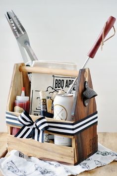 a wooden box with scissors and other items in it sitting on a table next to a napkin