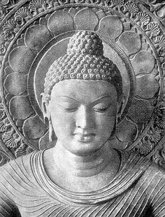 a black and white photo of a buddha statue in front of an intricately designed wall