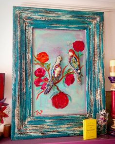 two birds sitting on flowers in a blue frame with pink and red roses painted on it