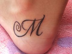 a small foot tattoo with the letter m on it's left side and an initial in the middle