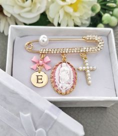 a white box with some gold and pink charms on it's side, next to a bouquet of flowers