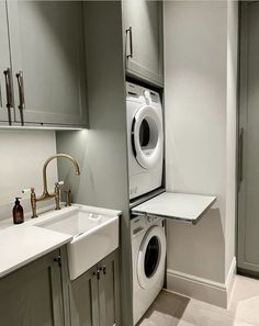 a washer and dryer are in the corner of this laundry room with gray cabinets