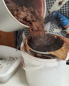 a person pouring water into a bucket filled with dirt