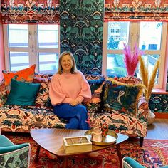 a woman sitting on top of a couch in a living room filled with colorful furniture