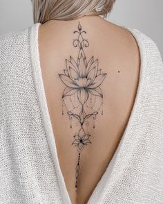 the back of a woman's neck with a flower tattoo on it