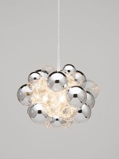 the chrome sphere chandelier is suspended from a white cord and has five balls on it