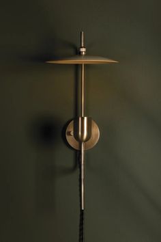 a wall mounted light with a chain hanging from it's side on a green wall