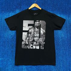 a black t - shirt with the number 50 cent on it is hanging on a blue background