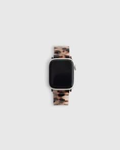 an apple watch sitting on top of a white surface with a brown and black animal print band