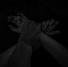 four hands reaching up towards each other in the dark