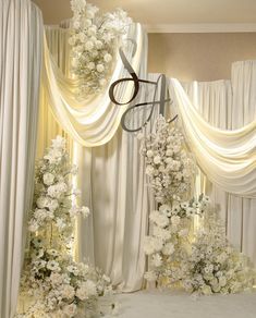 the wedding stage is decorated with white flowers and drapes