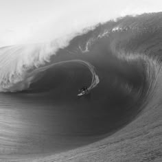 a man riding a wave on top of a surfboard under a large ocean wave