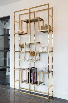 a book shelf with books on it in front of a white wall and black tile floor