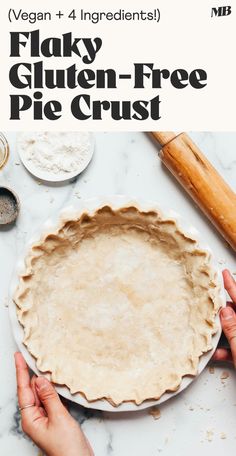 two hands holding a pie crust on top of a white counter with ingredients in the background