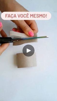 a person cutting paper with scissors on top of a white table next to a piece of cardboard