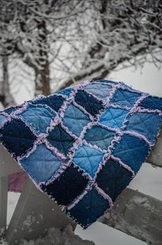 a blue and pink blanket sitting on top of a wooden fence next to a tree