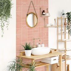 a bathroom with pink and white wallpaper, wooden shelves and a round mirror on the wall