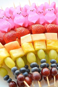 the fruit skewers are decorated with pink pigs and blueberries, raspberries, pineapples, grapes, and strawberries