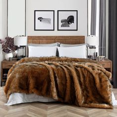 a bed with two pictures on the wall above it and a fur blanket in front of it