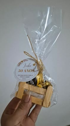 a hand holding a small wooden block filled with chocolate and wrapped in cellophane