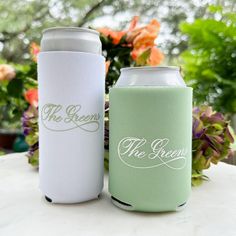 two green and white can coolers sitting next to each other on top of a table