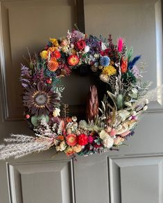 a wreath is hanging on the front door with feathers, flowers and other things around it