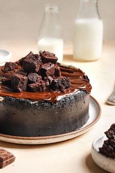 a chocolate cake sitting on top of a white plate next to milk and spoons