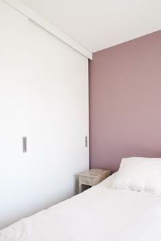 a white bed sitting in a bedroom next to a wall with pink paint on it