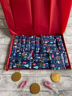 an open red case filled with candy canes next to two gold coins and one penny