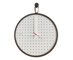 a clock hanging from the side of a white wall with red hands and numbers on it